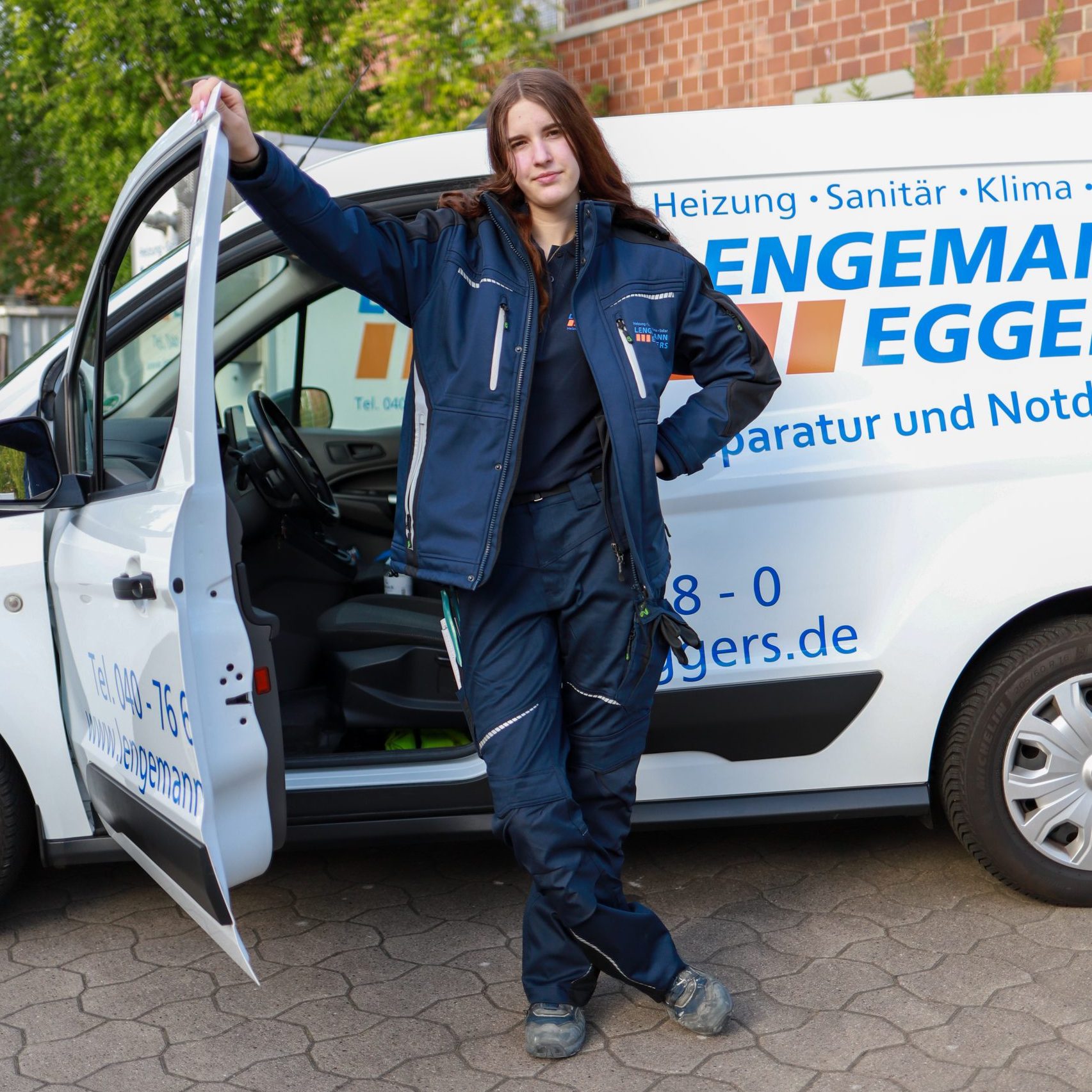 Handwerkerin steht vor der geöffneten Autotür
